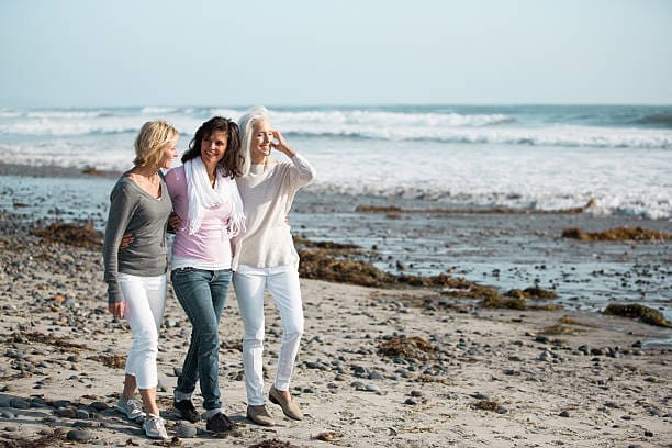 3 women walking on beach